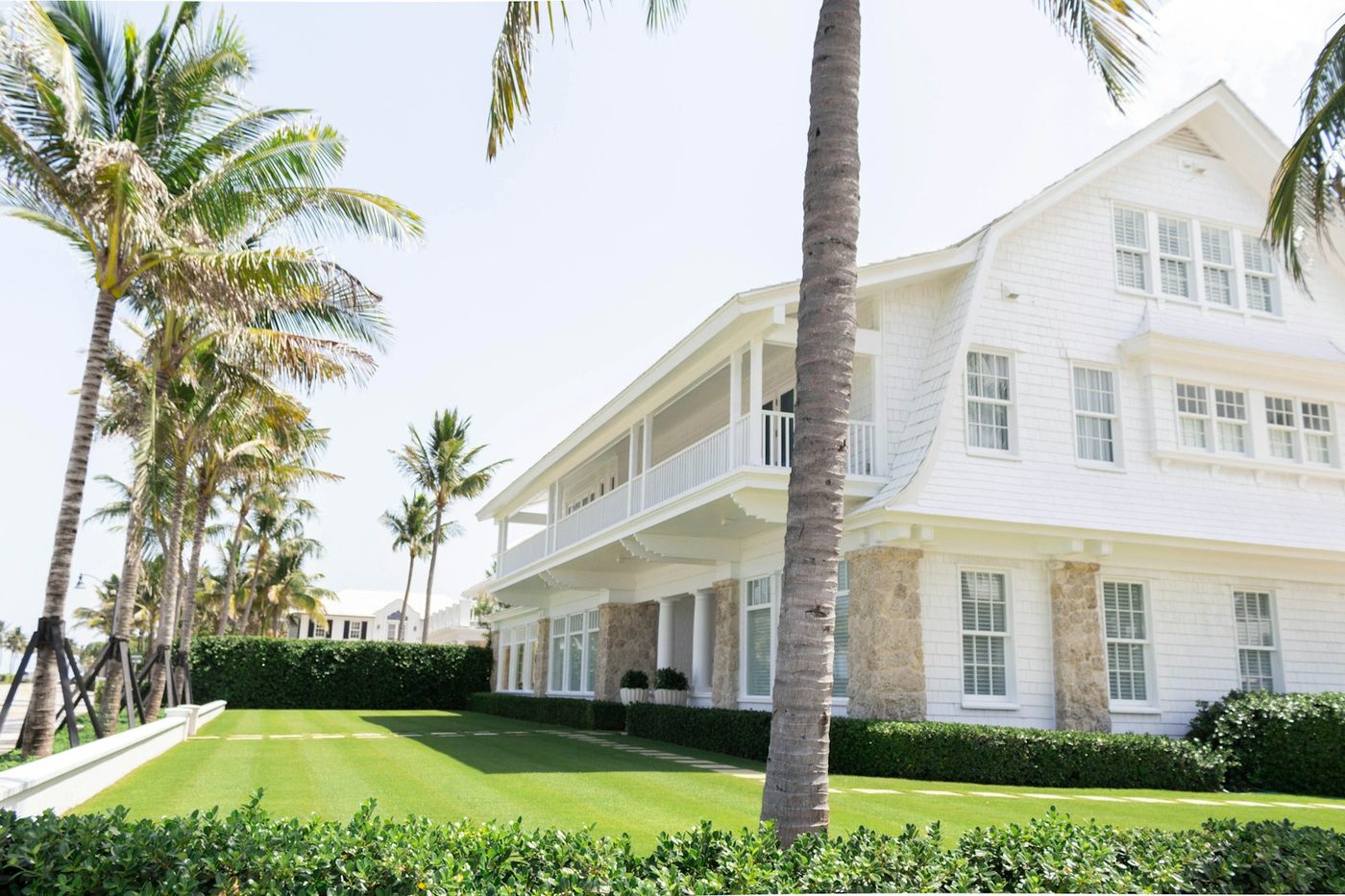 A white South Florida house behind palm trees on a clear day